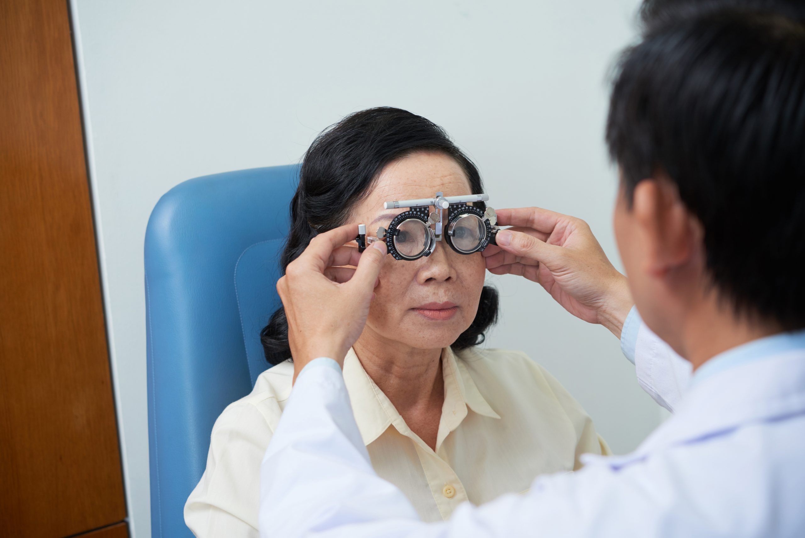 unrecognizable male ophtalmologist fitting trial lens frame senior female patient